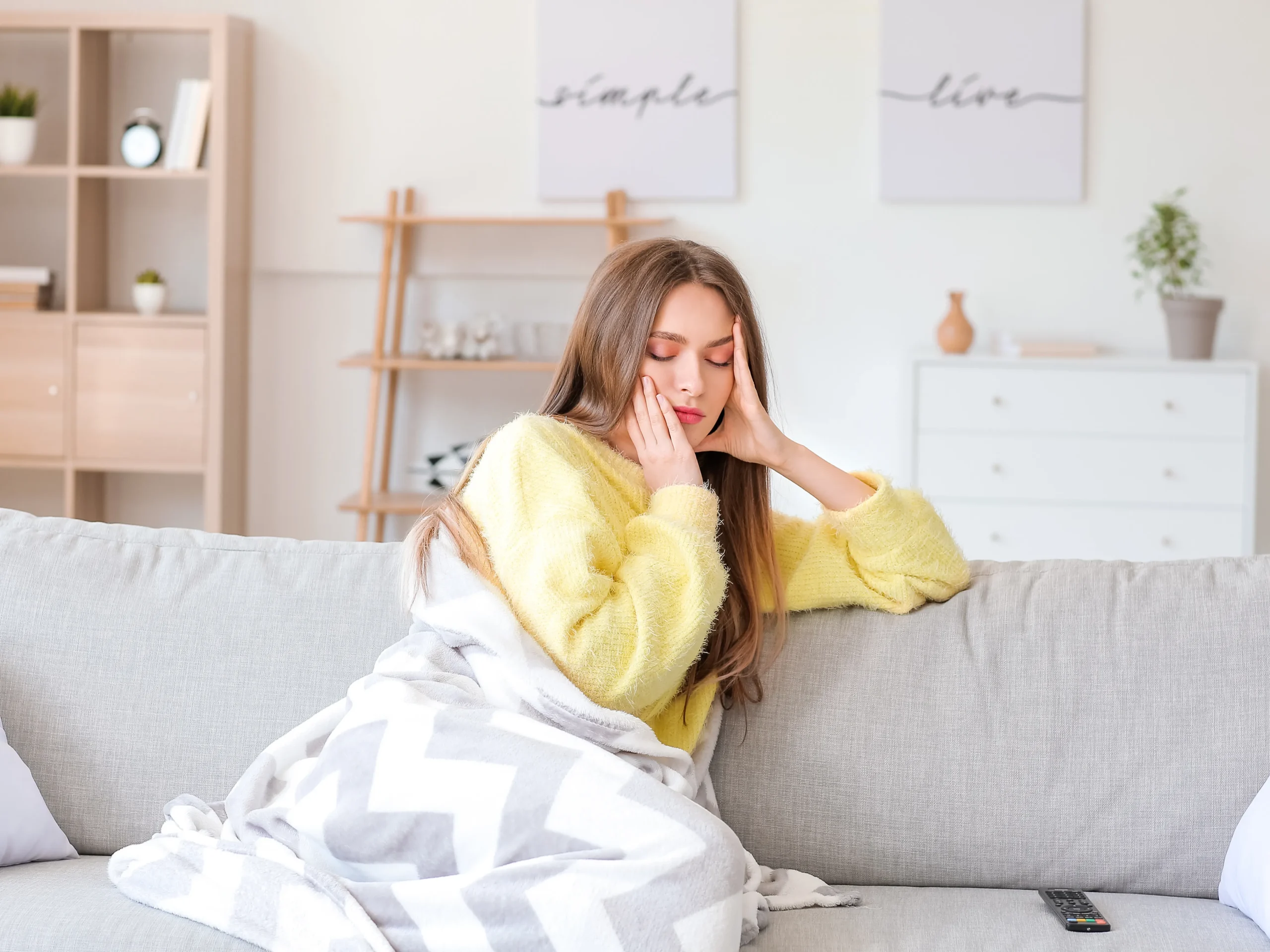 stressed woman sitting on couch with blanket