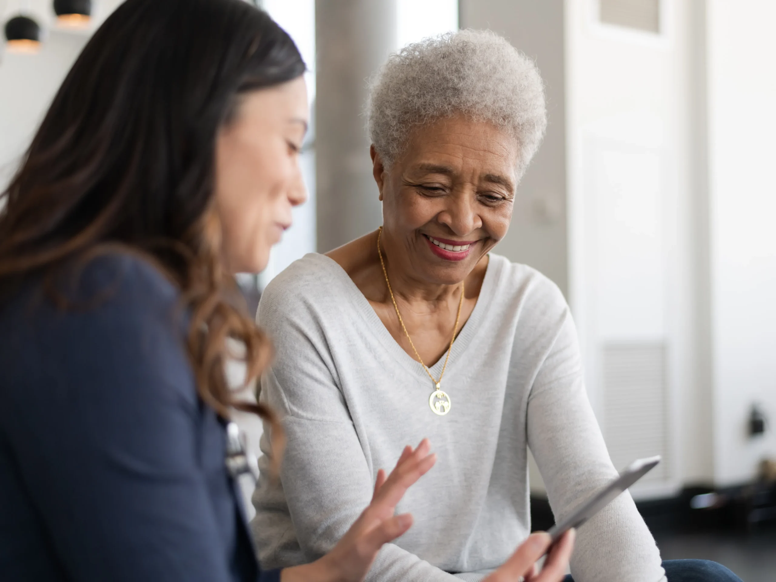 woman showing elderly woman how to use technology